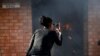 FILE - A women uses a cellphone to take pictures of a burning principal's school office in Mashau Dolly village in South Africa's northern Limpopo province, May 5, 2016. 