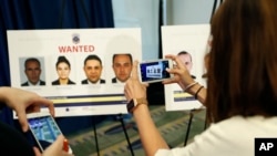 FILE - Reporters photograph wanted posters of people facing criminal charges before a news conference in Washington, June 15, 2017, about the May 16, 2017, altercation outside the Turkish Embassy in Washington during the visit of the Turkish president. 