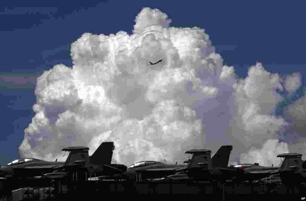 A commercial plane flies over the USS Ronald Reagan aircraft carrier in Hong Kong.