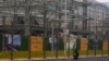 A delivery rider passes by workers laboring at a new residential building under construction in Beijing on March 1, 2025.