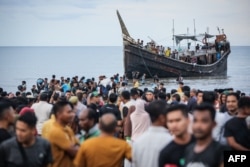 Pengungsi Rohingya yang baru tiba kembali ke perahu setelah masyarakat setempat memutuskan untuk mengizinkan mereka sementara mendarat untuk mendapatkan air dan makanan di Ulee Madon, Aceh, 16 November 2023. (Foto: AFP_
