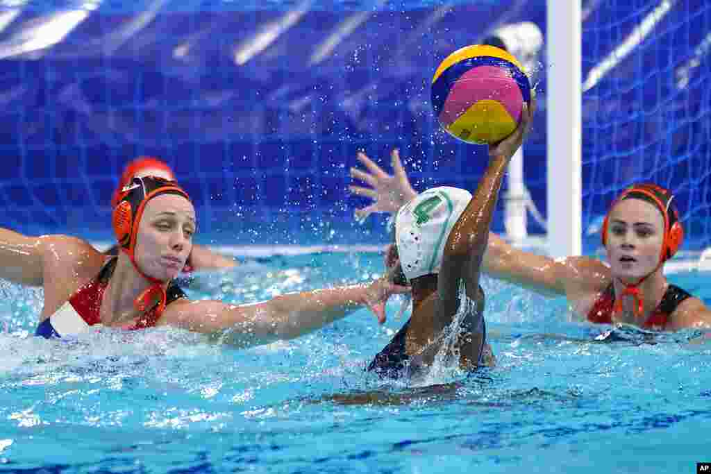 South Africa's Boati Motau (4) looks for a way past The Netherland's Maartje Keuning, left, and Brigitte Sleeking, right, during a preliminary round women's water polo match at the 2020 Summer Olympics, Friday, July 30, 2021, in Tokyo, Japan. (AP Photo/Mark Humphrey)