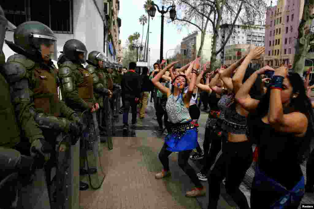 Demonstrators perform a dance in front of riot policemen during a march called by students to request changes in the education system in Santiago, Chile, Sept. 5, 2017.