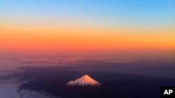 FILE - New Zealand's Taranaki Maunga, previously known as Mount Taranaki, has a warm glow lighting the snow peak, June 12, 2011.