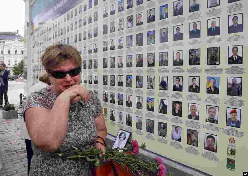 A woman cries at a memorial wall with photos of servicemen killed in the conflict with pro-Russian separatists in the country's east, in Kyiv, Ukraine.