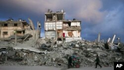 Yon moun pouse yon kabwet devan yon kay ki pasyelman kanpe ak dra ki sevi kom miray nan yon zon lame Izrayelyen preske ratibwaze net pandan ofansiv li nan Gaza siti, 5 Fevriye, 2025.