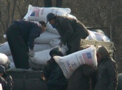 2008년 12월 북한 신의주 주민들이 미국에서 지원한 식량을 트럭에서 내리고 있다. 식량 자루에 'USAID(미국제개발처)' '미국에서 보내온 선물' 이란 문구가 씌여있다. (자료사진)