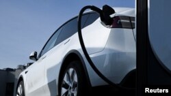 ແຟ້ມພາບ: ລົດໄຟຟ້າຍີ່ຫໍ້ Tesla ກຳລັງຈອດສາກໝໍ້ໄຟ ຢູ່ສະຖານທີ່ສາກໝໍ້ໄຟແຫ່ງນຶ່ງ. March 20, 2024. REUTERS/Annegret Hilse/File Photo.