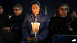 A woman holds a candle as Cardinal Robert Francis Prevost, Prefect of the Dicastery for Bishops, leads the recitation of the Holy Rosary for Pope Francis' health in St Peter's Square at the Vatican, March 3, 2025. 