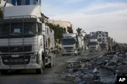 Truk bantuan kemanusiaan memasuki Jalur Gaza melalui penyeberangan Kerem Shalom dari Mesir, saat kesepakatan gencatan senjata antara Israel dan Hamas mulai berlaku, Minggu, 19 Januari 2025. (Jehad Alshrafi/AP)