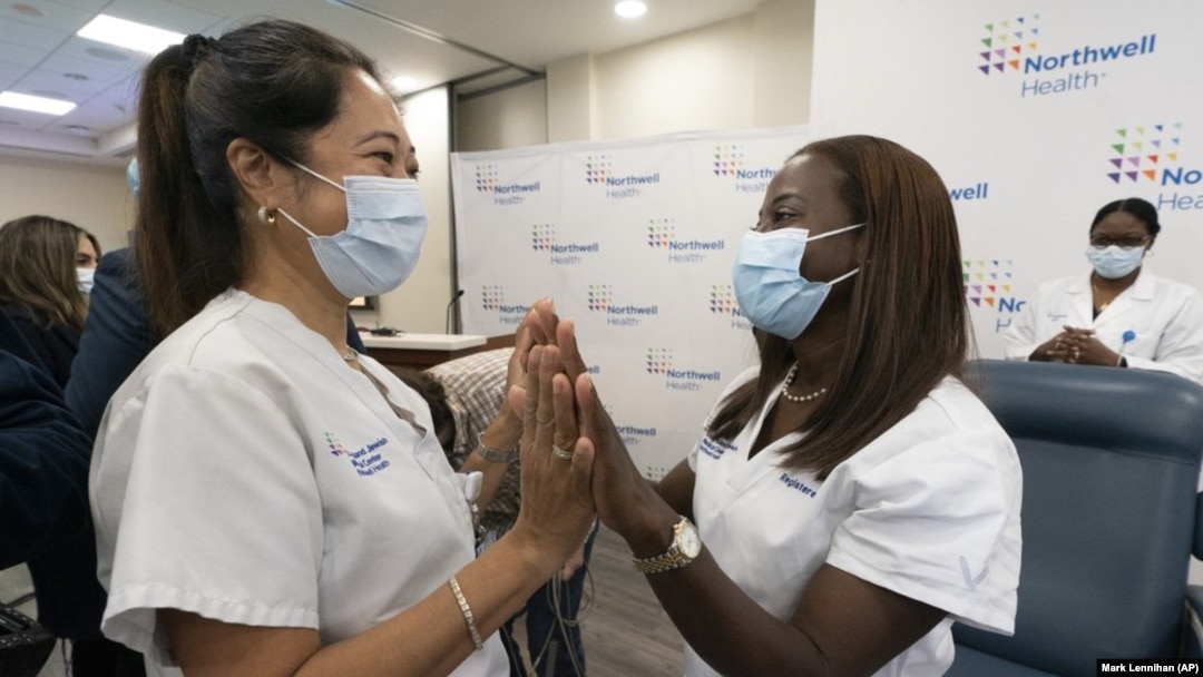 Nurse Annabelle Jimenez, left, congratulates nurse Sandra Lindsay after she is inoculated with the Pfizer-BioNTech COVID-19 vaccine, Monday, Dec. 14, 2020, at the Jewish Medical Center, in the Queens borough of New York. (AP Photo/Mark Lennihan, Pool)