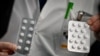 FILE - In this photo taken on Feb. 26, 2020, medical staff at the IHU Mediterranee Infection Institute in Marseille, France, show packets of Nivaquine, tablets containing chloroquine and Plaqueril, tablets containing hydroxychloroquine. 