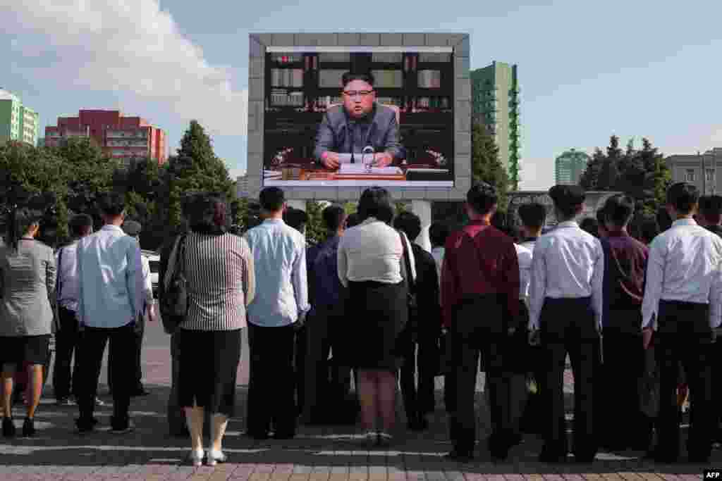 Spectators listen to a television news broadcast of a statement by North Korean leader Kim Jong-Un, before a public television screen outside the central railway station in Pyongyang.