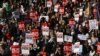 Manifestantes seguram cartazes enquanto se reúnem em Trafalgar Square apelando ao fim da violência masculina contra as mulheres, em Londres, a 8 de março de 2025, para assinalar o Dia Internacional das Mulheres.