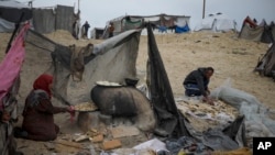 Mona Al-Zebda, deslocada da Cidade de Gaza, pepara pão num campo de deslocados palestinianos em Muwasi, Rafah, no sul da Faixa de Gaza, 24 de fevereiro de 2025.