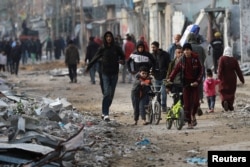 Palestinians walk on a destroyed street after Israeli forces withdrew from a part of Nuseirat following a ground operation amid the ongoing conflict between Israel and Hamas in Nuseirat, central Gaza Strip, Nov. 29, 2024.