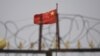 资料照：中国新疆喀什南部的一个铁丝网后的住宅区中飘扬的国旗。（2019年6月4日）